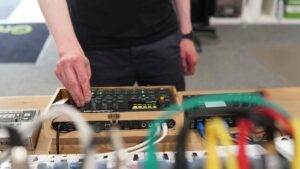 A man working with electronic music equipment, adjusting settings and controls.