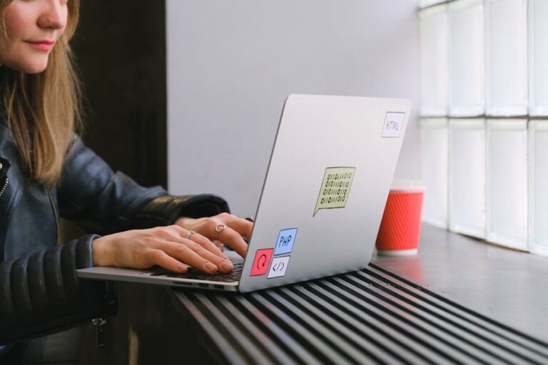 Woman using a laptop by a window in a cafe with a coffee. Ideal for tech and lifestyle themes.