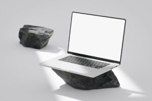 Elegant laptop with blank screen balanced on rocks in a minimalist setting.