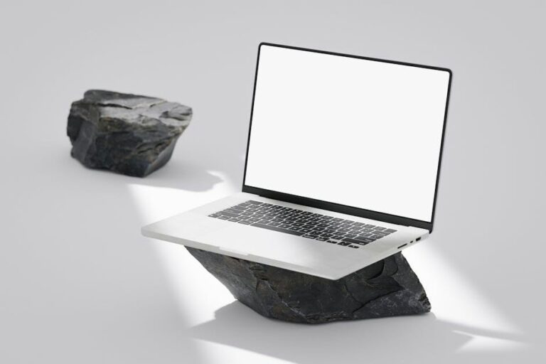 Elegant laptop with blank screen balanced on rocks in a minimalist setting.
