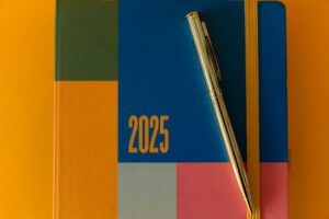 A vibrant 2025 planner with a pen on a colorful backdrop, ideal for organization.