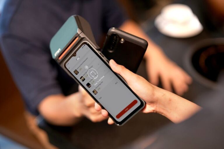 Close-up of a smartphone making a contactless payment at a modern payment terminal in a retail environment.