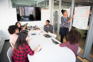 A multicultural office team engages in a collaborative brainstorming session around a conference table.
