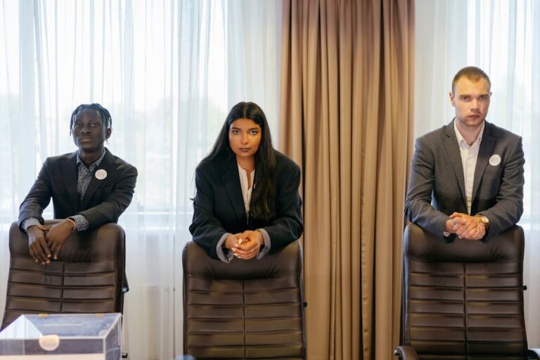Three diverse professionals in suits in a conference room, expressing confidence and teamwork.