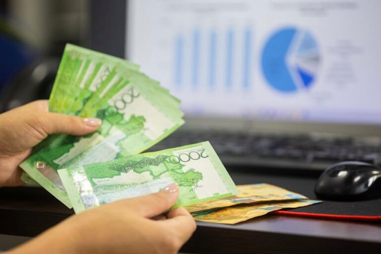 Hands counting cash with financial charts in background, indicating business or finance theme.