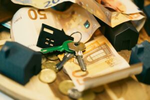 Euro currency with house keys and miniature models, symbolizing real estate investment.