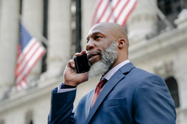 Confident businessman in a suit talking on phone with American flags in the background.