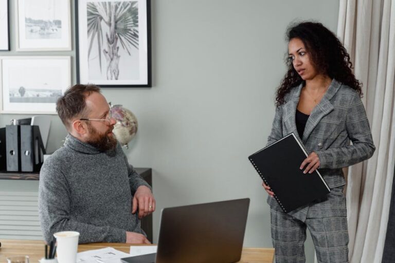 A man and woman discuss work in a stylish office environment with modern decor.