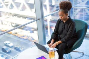 African American woman working on a laptop in a modern office setting, emphasizing professional and technology themes.