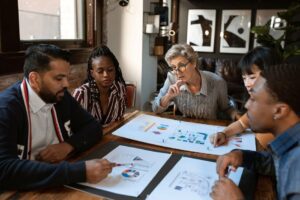 A multicultural team engaged in a business meeting with charts and graphs on the table.