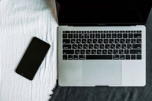 Overhead view of a laptop and smartphone arranged on a textured surface.