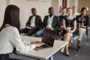 Professional woman giving a presentation to a diverse group of colleagues in an office.