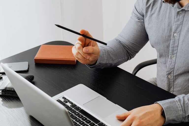 Close-up of a professional working at a desk with a laptop and notebook, symbolizing business and productivity.