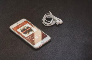 A smartphone with earbuds playing music on a sleek dark surface, ideal for lifestyle and technology themes.