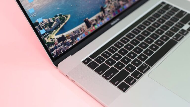 Close-up view of a sleek laptop with cityscape wallpaper on a pink background.