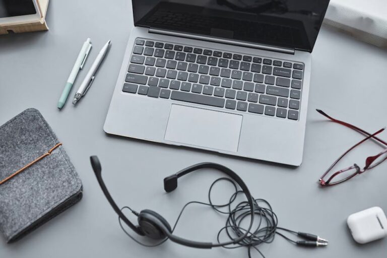 Overhead view of a modern workspace with a laptop, headphones, and stationery.
