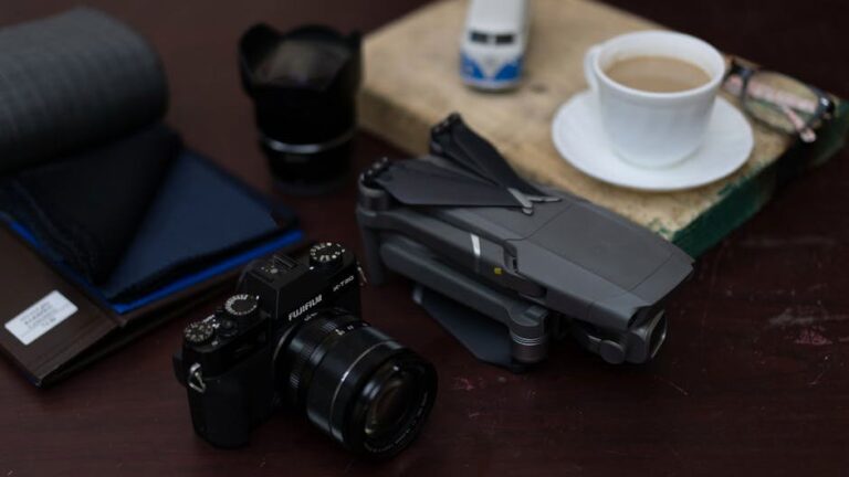 A close-up view of tech gadgets including a camera and drone, paired with a coffee cup on a desk, highlighting modern lifestyle.