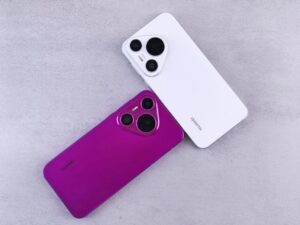 Two Huawei smartphones, one white and one purple, on a textured concrete surface.
