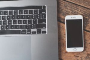 A sleek laptop and smartphone on a wooden table, showcasing modern technology essentials.