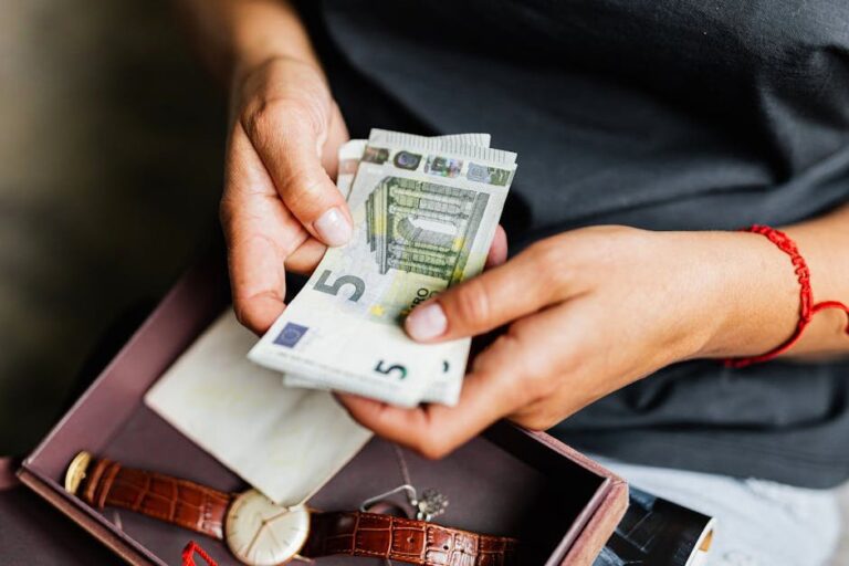 Close-up of hands counting euro notes above a wristwatch in a box.